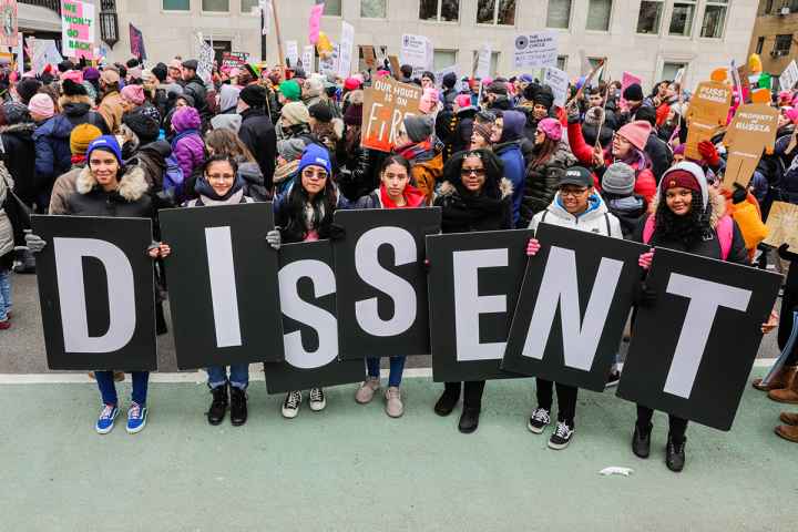 Protesters holding signs that say dissent