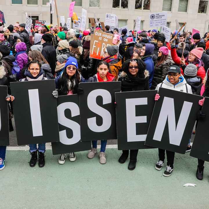 Protesters holding signs that say dissent